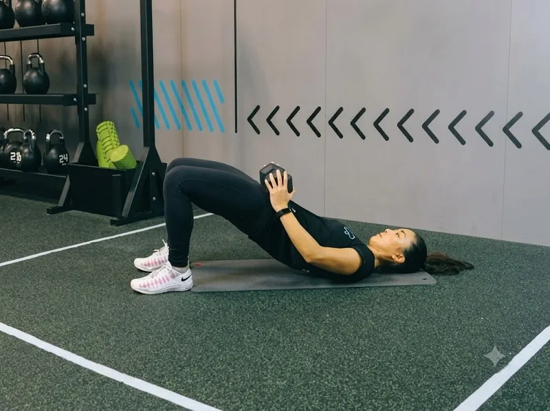 Glute bridge với tạ đơn giúp tăng cường sức mạnh cơ mông.